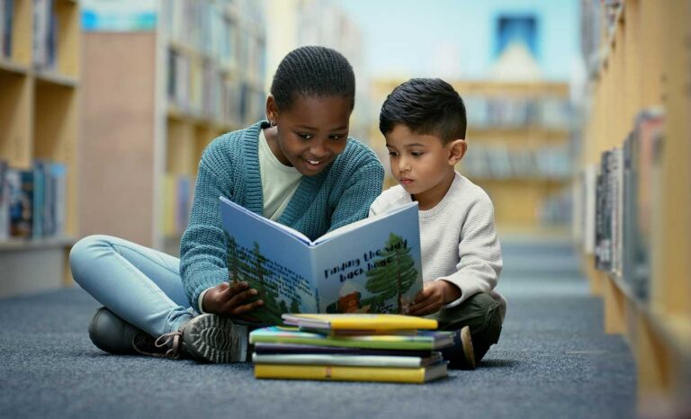 Kids reading a book together in library