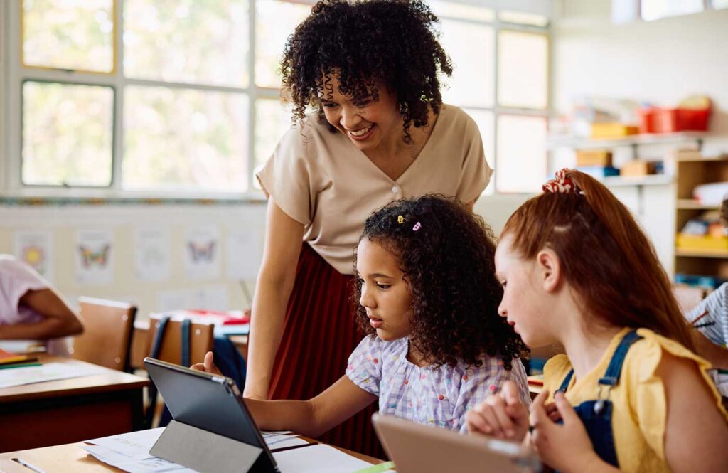 Teacher with children in classroom working on a tablet.