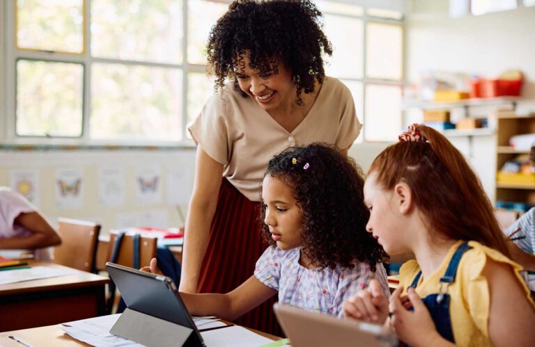 Teacher with children in classroom working on a tablet.